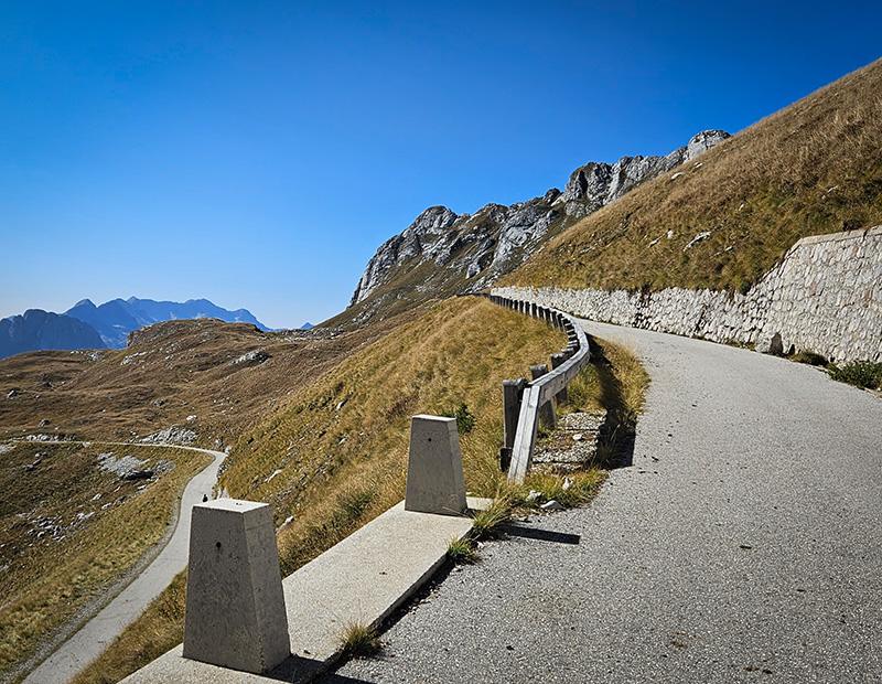 Epic, winding paved road of a high mountain pass in the Julian Alps, Slovenia, showcasing the steep climbs and dramatic scenery of a challenging road cycling route.