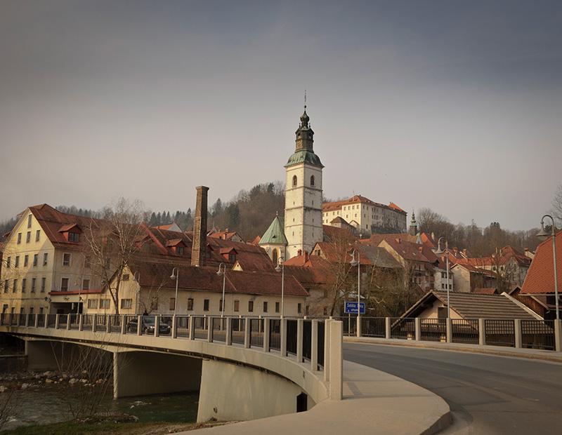 The prominent church tower and historic architecture of Škofja Loka, Slovenia, a picturesque cultural stop along a Helia self-guided cycling tour route.